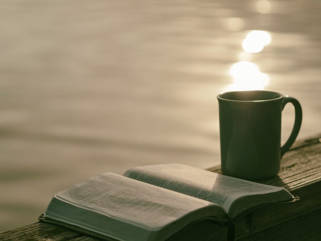 um livro aberto com uma caneca ao lado na ´praia